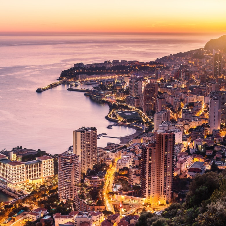 Panorama view of monaco city, harbour, sea, beach and rock at sunset. illuminated by the sun and lights of the place. beautiful colours and scenic picture of this famous place.