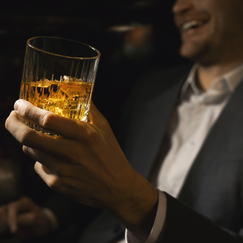 happy businessman with glass of whiskey in gentlemen club bar